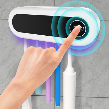 Hand pressing a touch-activated button on a wall-mounted  tooth brush sterilizer. 