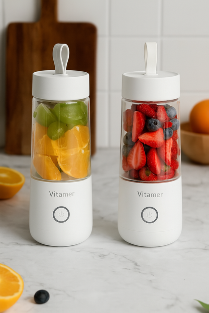 Two white Vitamer blenders filled with fresh fruit on a marble countertop.