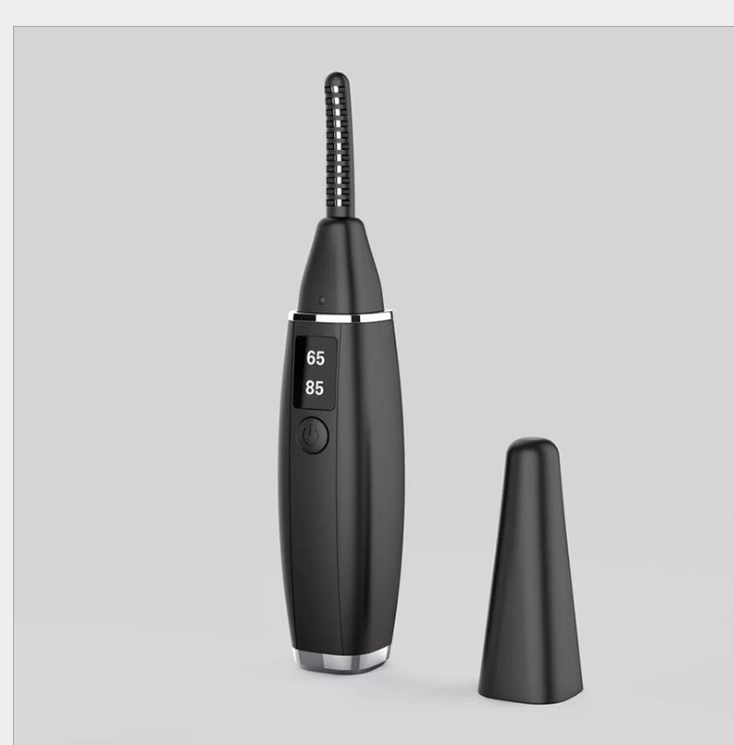 Black heated eyelash curler with digital temperature display (65°C and 85°C) and a detachable protective cap placed beside it.