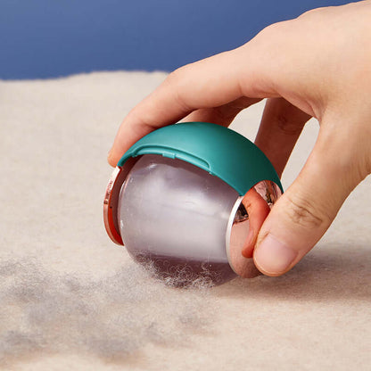 Hand using green reusable lint remover ball to lift pet hair from beige carpet with blue background