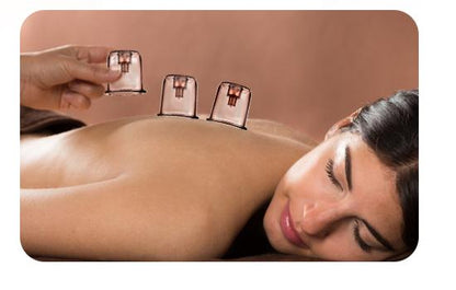 Woman using 4-in-1 Gua Sha facial and body device on her back for cupping therapy.
