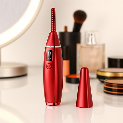 Heated eyelash curler in red,  standing on vanity table beside mirror.